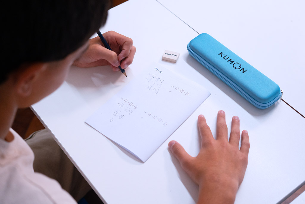 Alumno resolviendo ejercicios avanzados de matemáticas en un cuaderno Kumon, siguiendo un aprendizaje gradual y estructurado