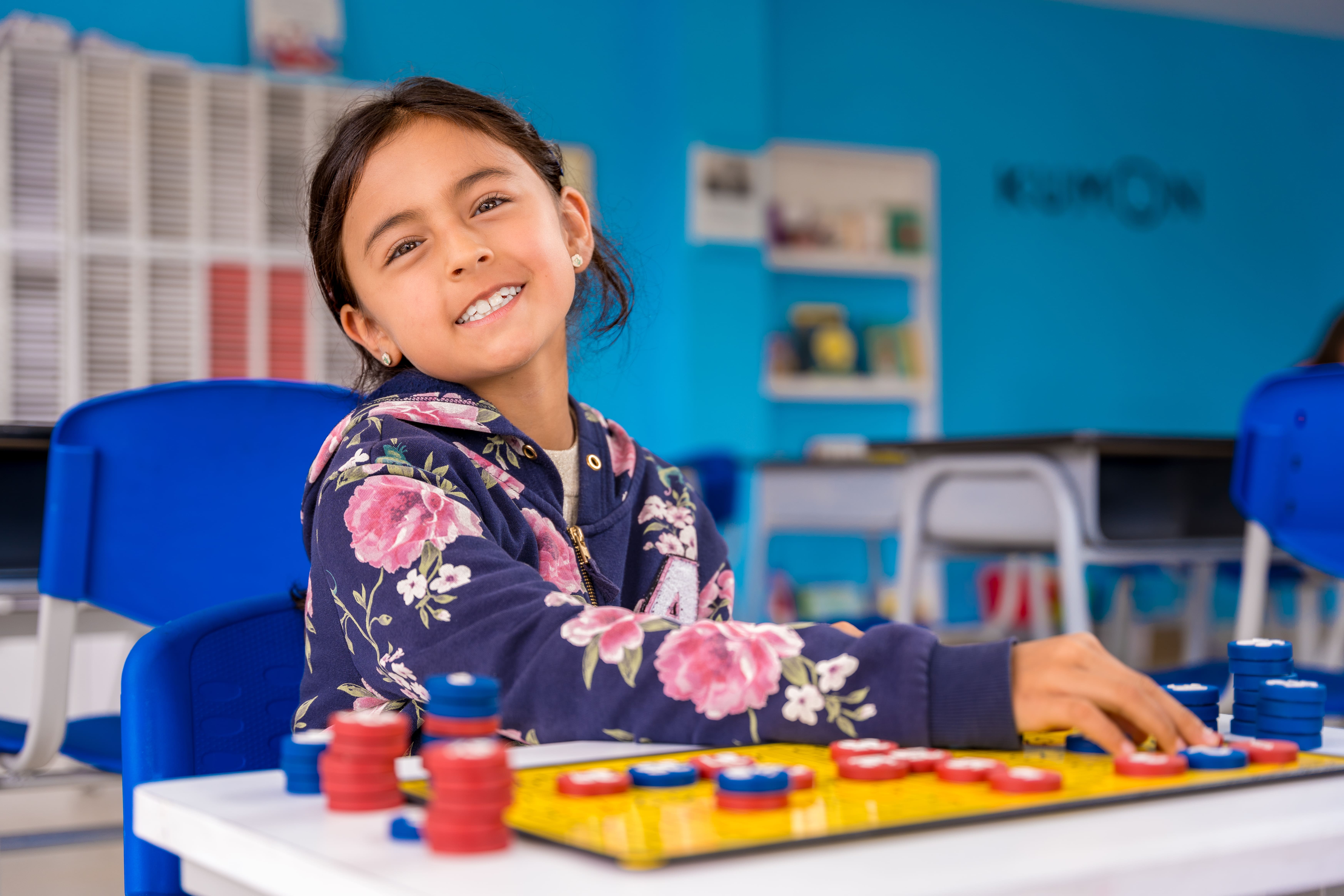 Niña estudiando matemáticas básicas con tablero magnético en un centro Kumon, disfrutando del aprendizaje